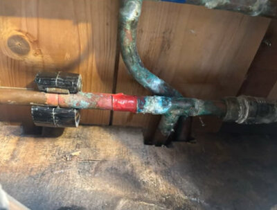 Corroded copper pipework repaired with a new compression joint under a floor