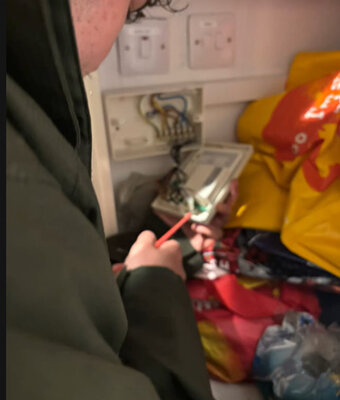 Electrician working inside a consumer unit during an electrical repair