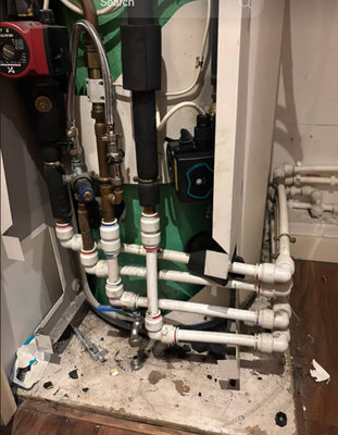 Heating system pipework, pump and valves exposed behind a boiler panel