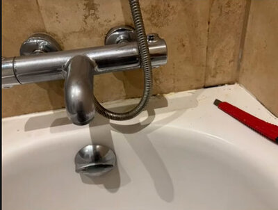 Bath mixer tap and shower hose fitted against a tiled surround
