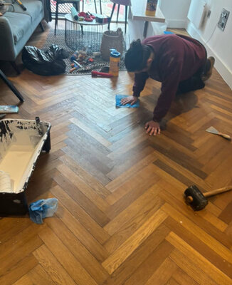 Fitter laying herringbone parquet flooring in a living room