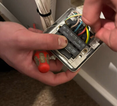 Electrician wiring a fused spur before refitting the faceplate