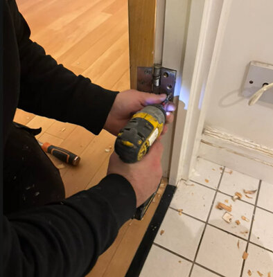 Fitting a new door hinge with a cordless drill during carpentry work