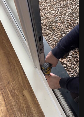 Adjusting a UPVC door frame with a drill during a lock and door repair